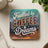 "Fuelled by Coffee & Dreams" text on a geometric patterned coaster.