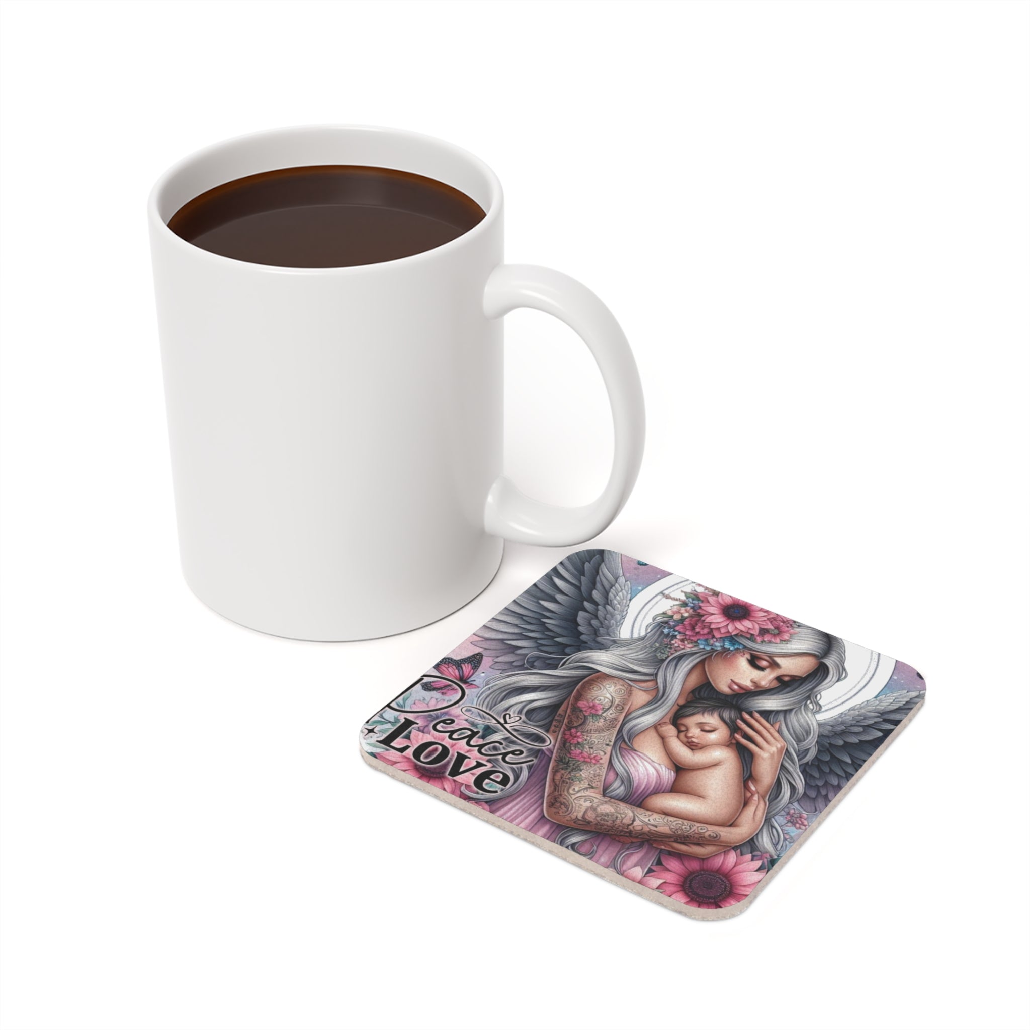 Square coaster with angel holding baby, "Peace Love" text, next to coffee mug.