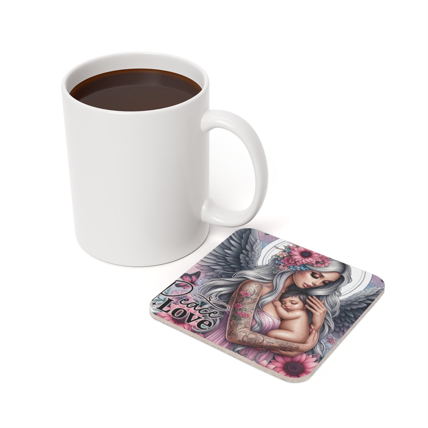 Square coaster with angel holding baby, "Peace Love" text, next to coffee mug.