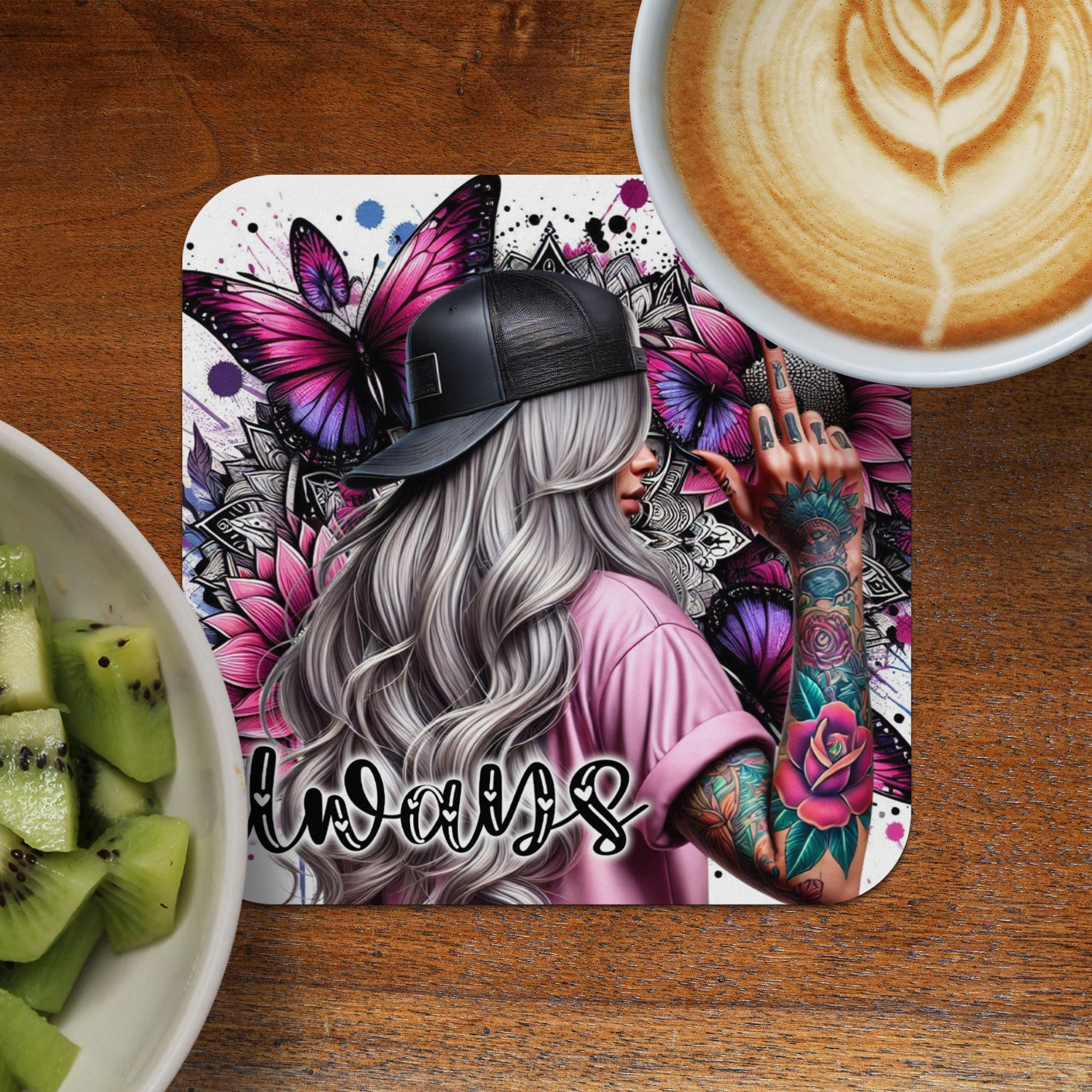 Pink t-shirt and butterfly art on coaster with latte and kiwi.