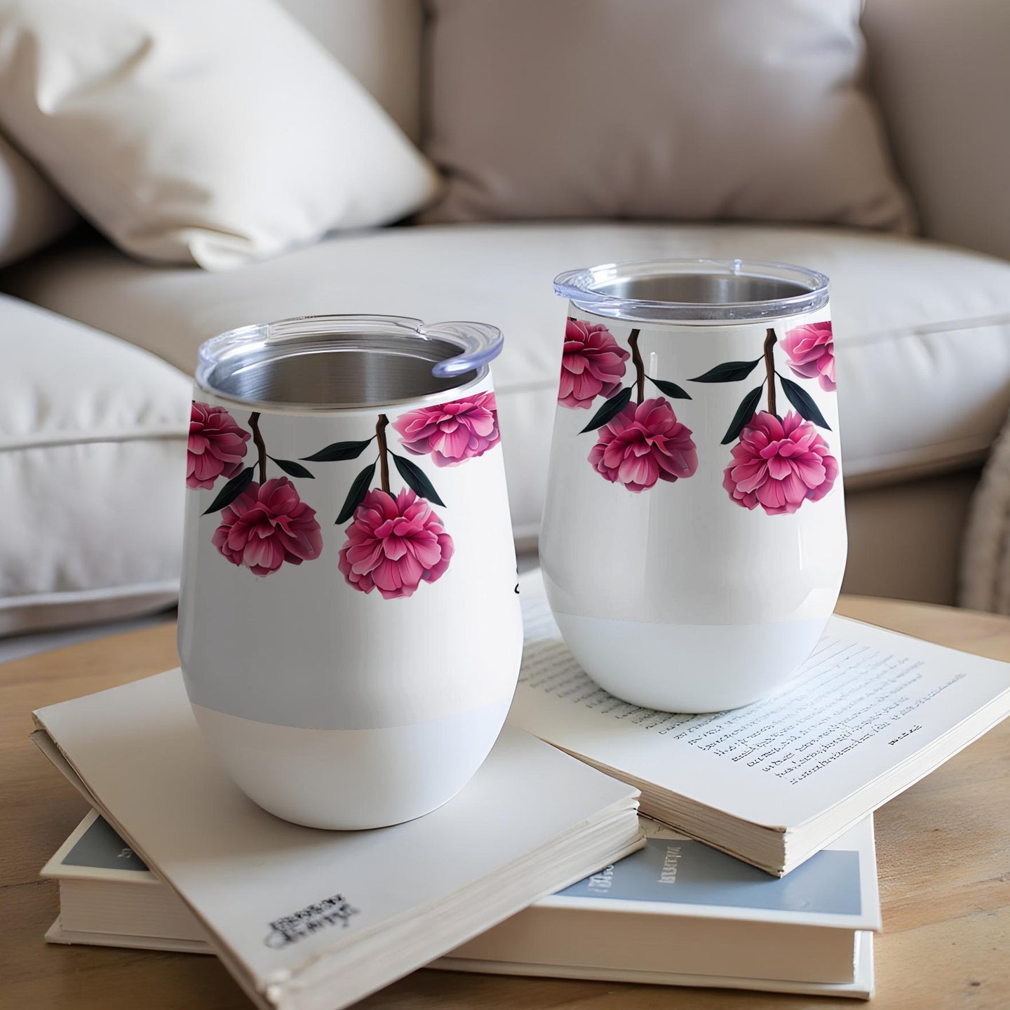 Two white tumblers with pink floral designs sit on books.