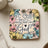 Square coaster with floral border and text "Be Still and Know That I Am God".