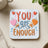 Coaster with "YOU are ENOUGH" text and colorful hearts.