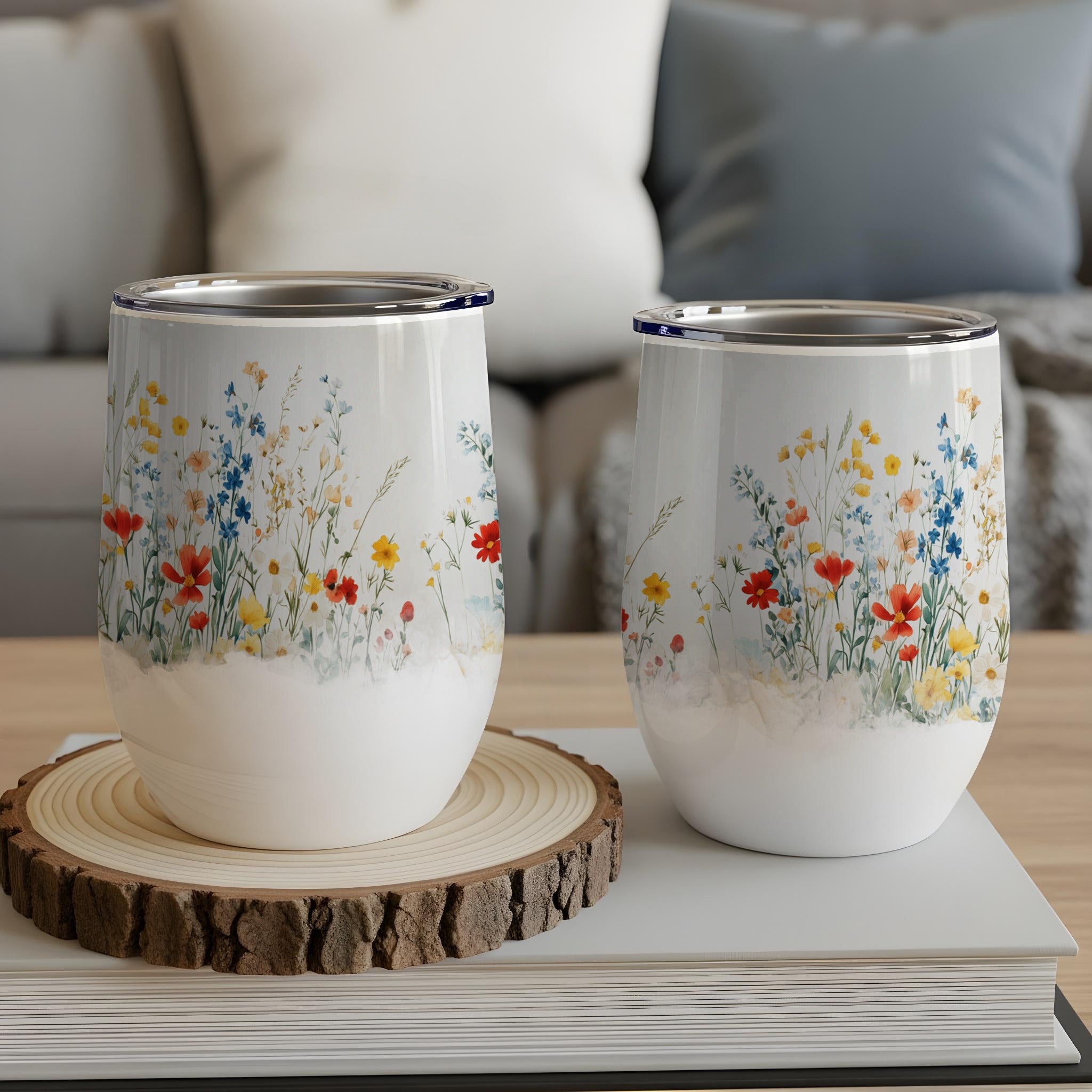 Two tumblers with a floral wildflower pattern on a wooden coaster.