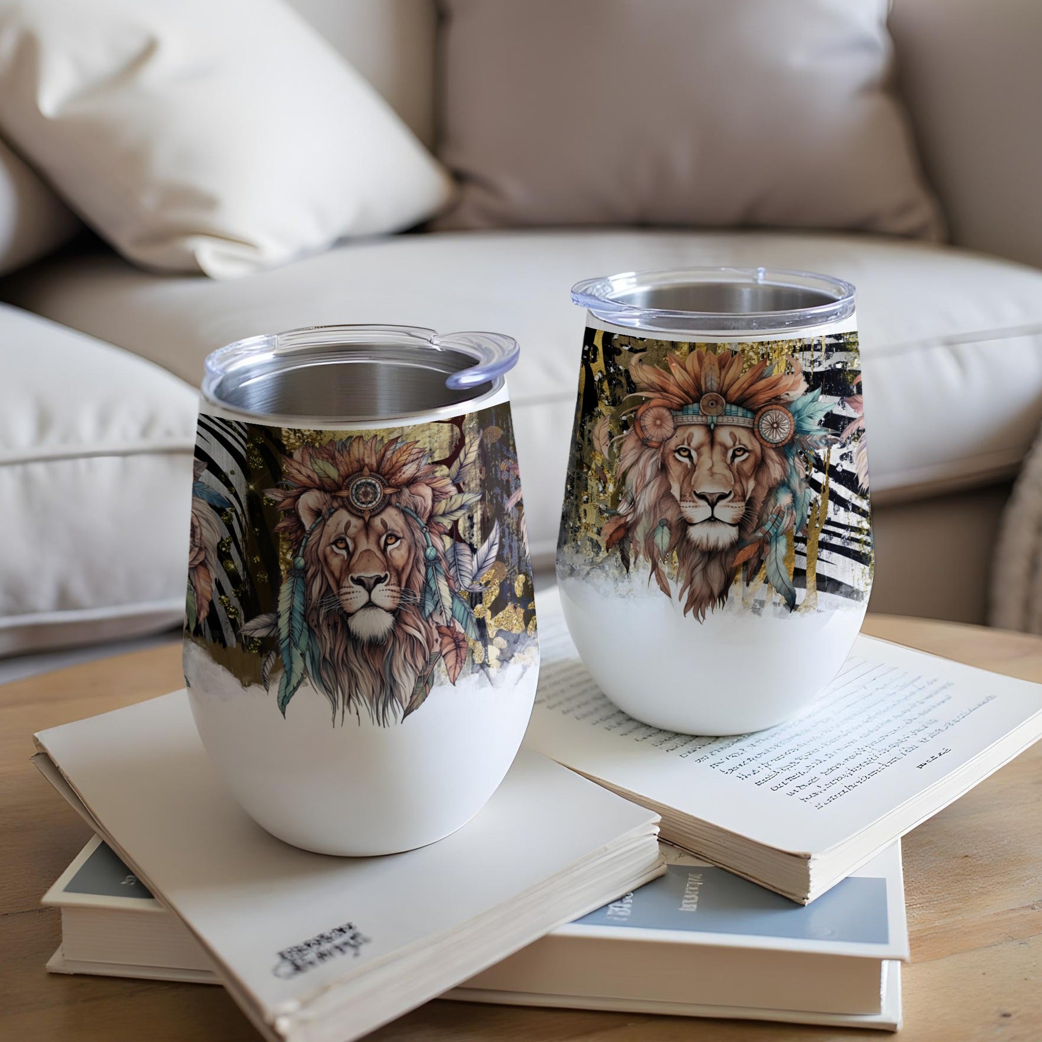 Two insulated wine tumblers with a colorful lion design rest on books.