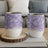 Two stemless wine tumblers with iridescent feather pattern on a wooden coaster.