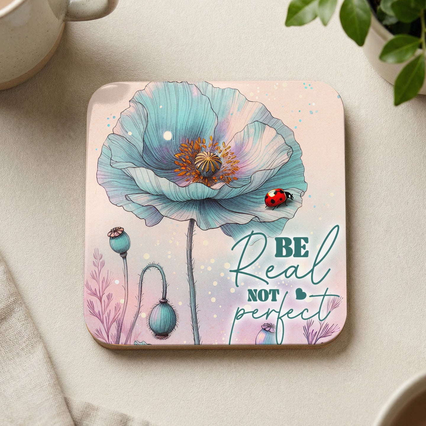 Square coaster with a blue poppy and a ladybug, "Be Real Not Perfect" text.