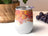 White stemless tumbler with colorful abstract alcohol ink design and grapes.