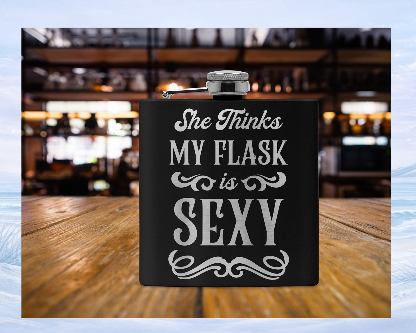 Black flask with text "She Thinks My Flask is Sexy" on wooden table.