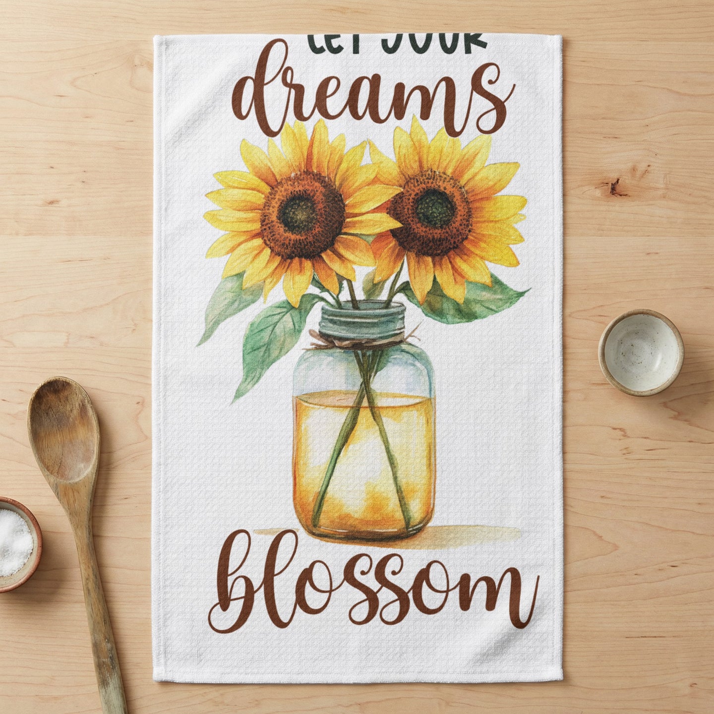 Sunflowers in a jar with "Let Your Dreams Blossom" text on a tea towel.