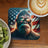 Bigfoot wearing sunglasses reflecting American flag on a coaster with coffee and kiwi.