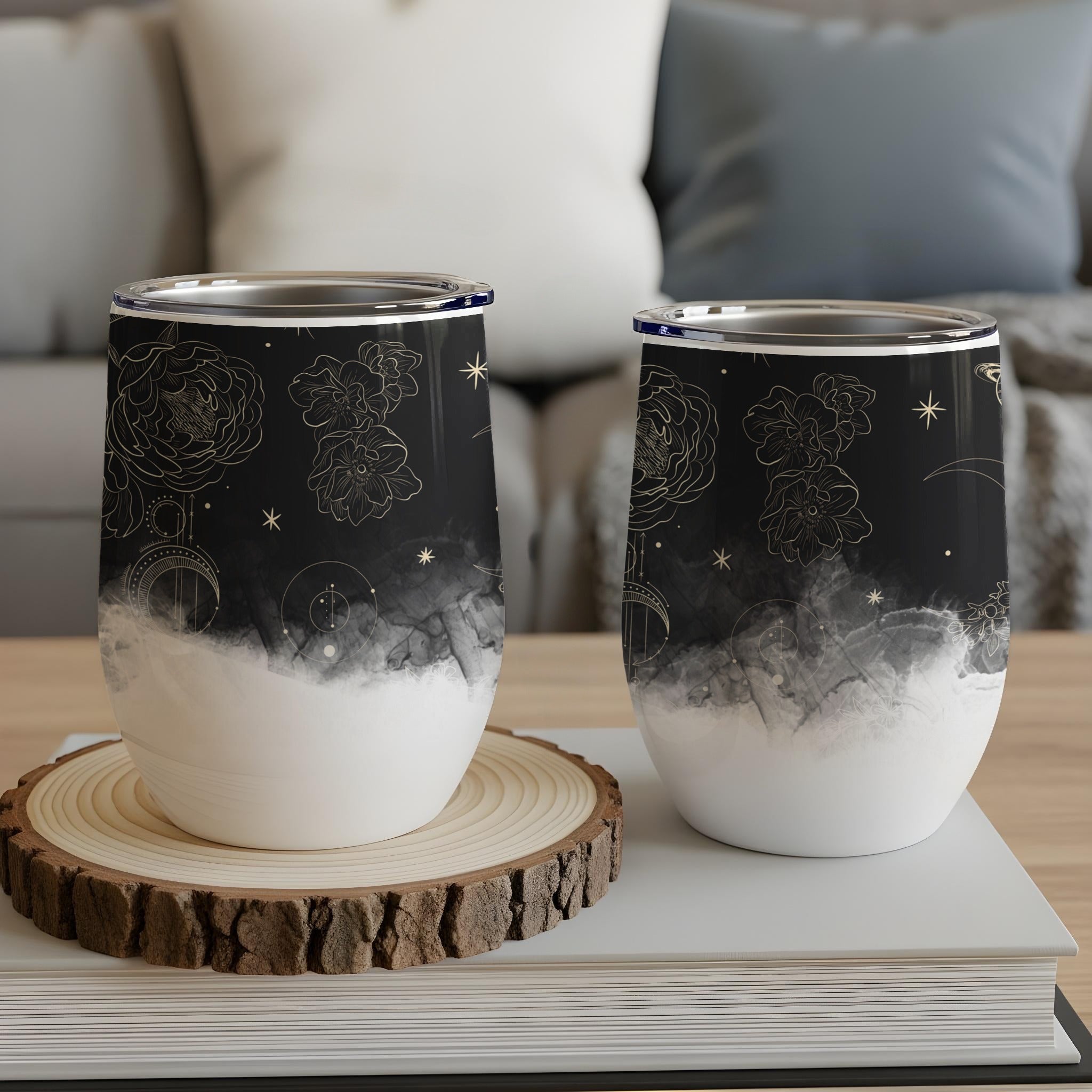 Black and white floral and celestial pattern insulated tumblers on wooden coaster.