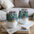 Two floral patterned tumblers with clear lids sit on books.