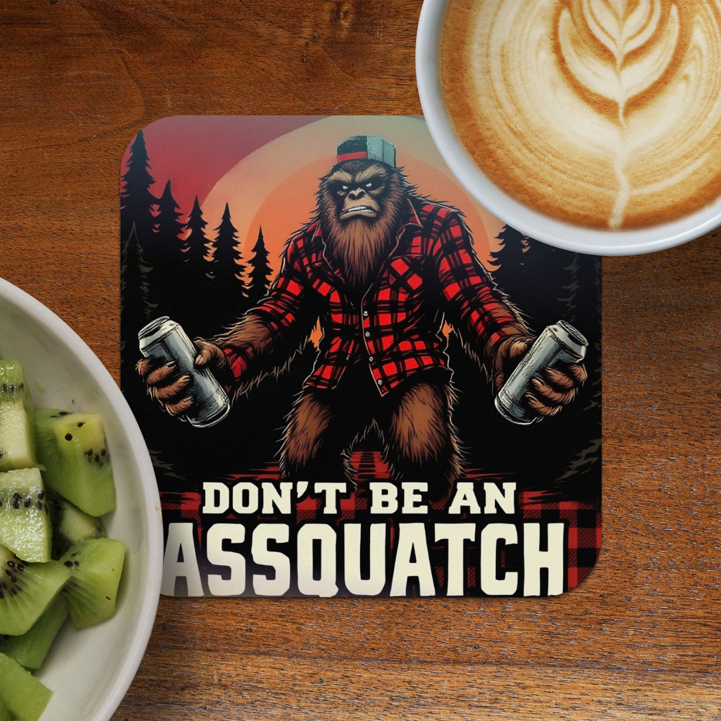 Bigfoot in flannel holding two cans, text reads "DON'T BE AN ASSQUATCH".