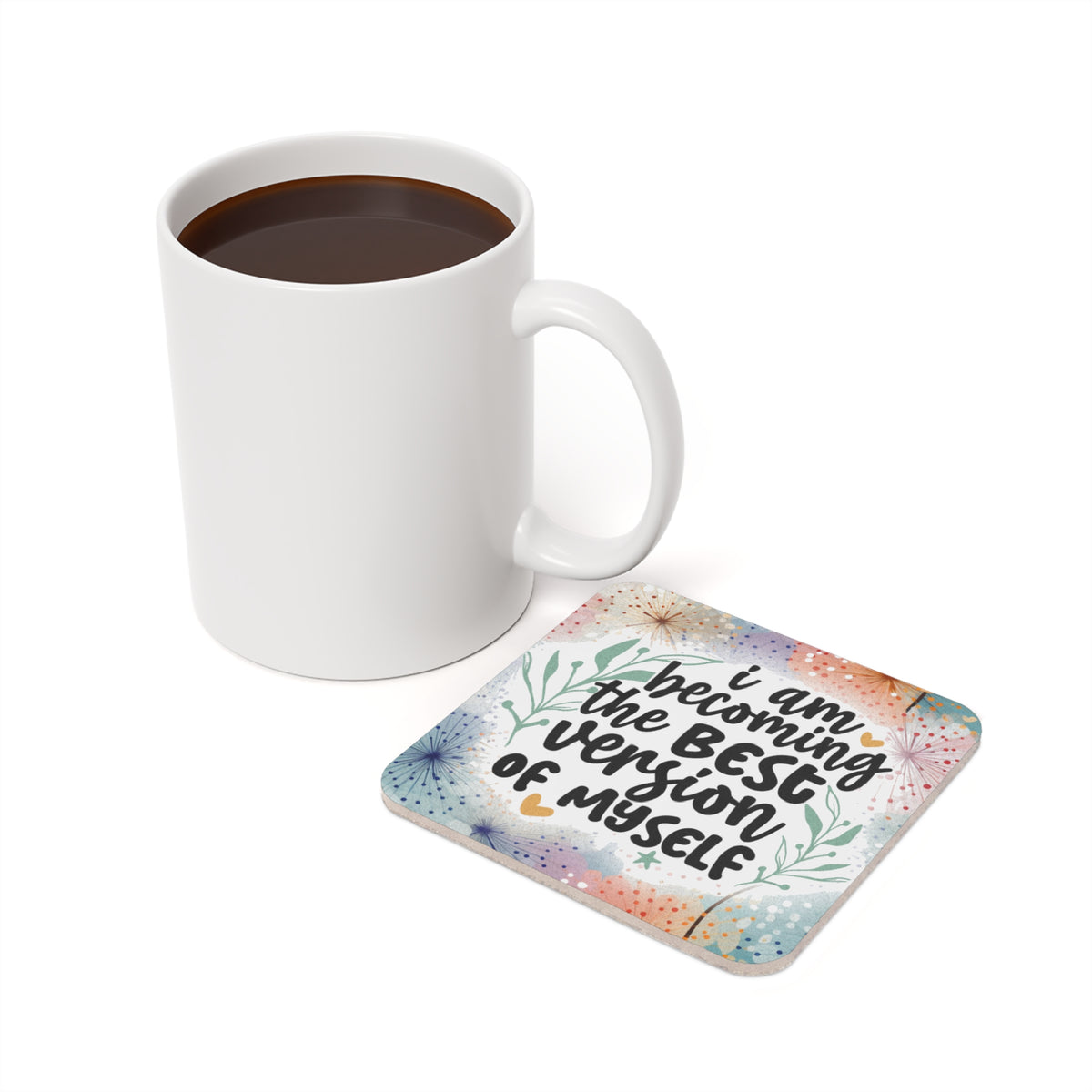 White mug next to coaster with text "I am becoming the best version of myself".