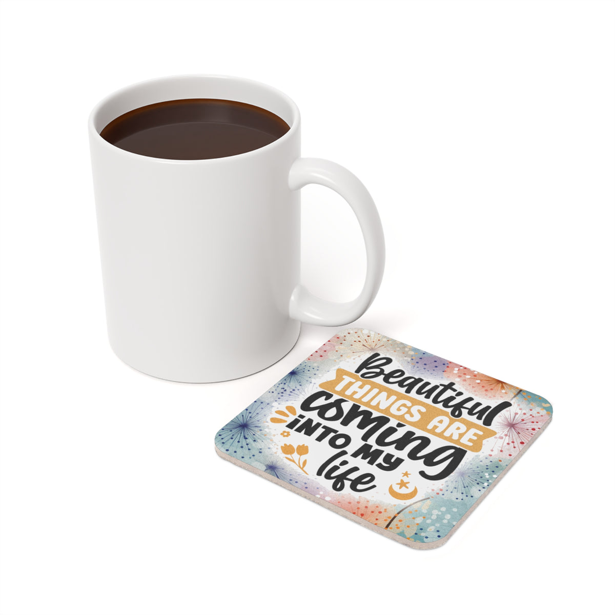 White mug of coffee next to a square coaster with "Beautiful things are coming into my life" text.