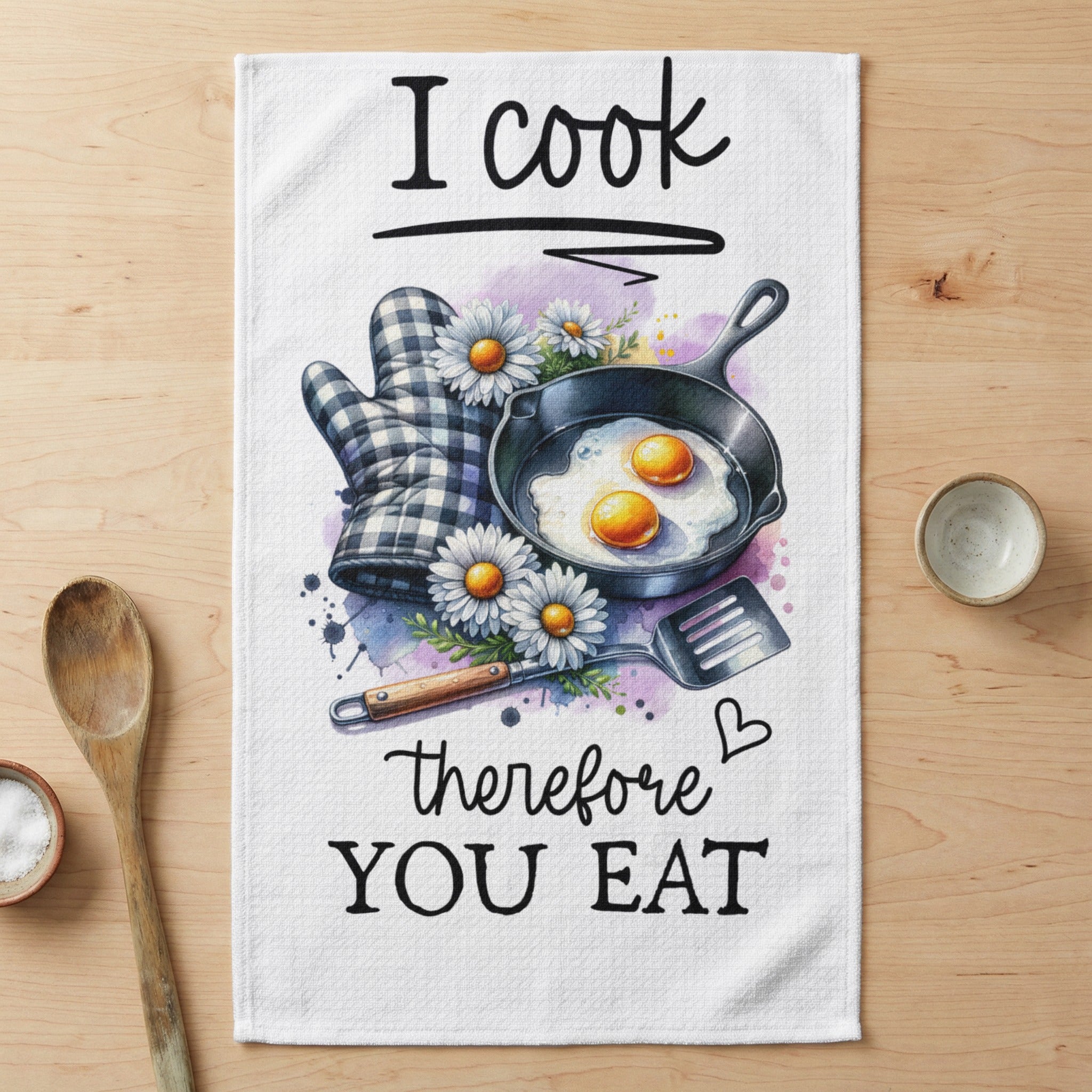 Tea towel with "I cook therefore you eat" text, fried eggs, and kitchen utensils.