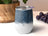 White tumbler with denim-texture top and purple grapes in background.