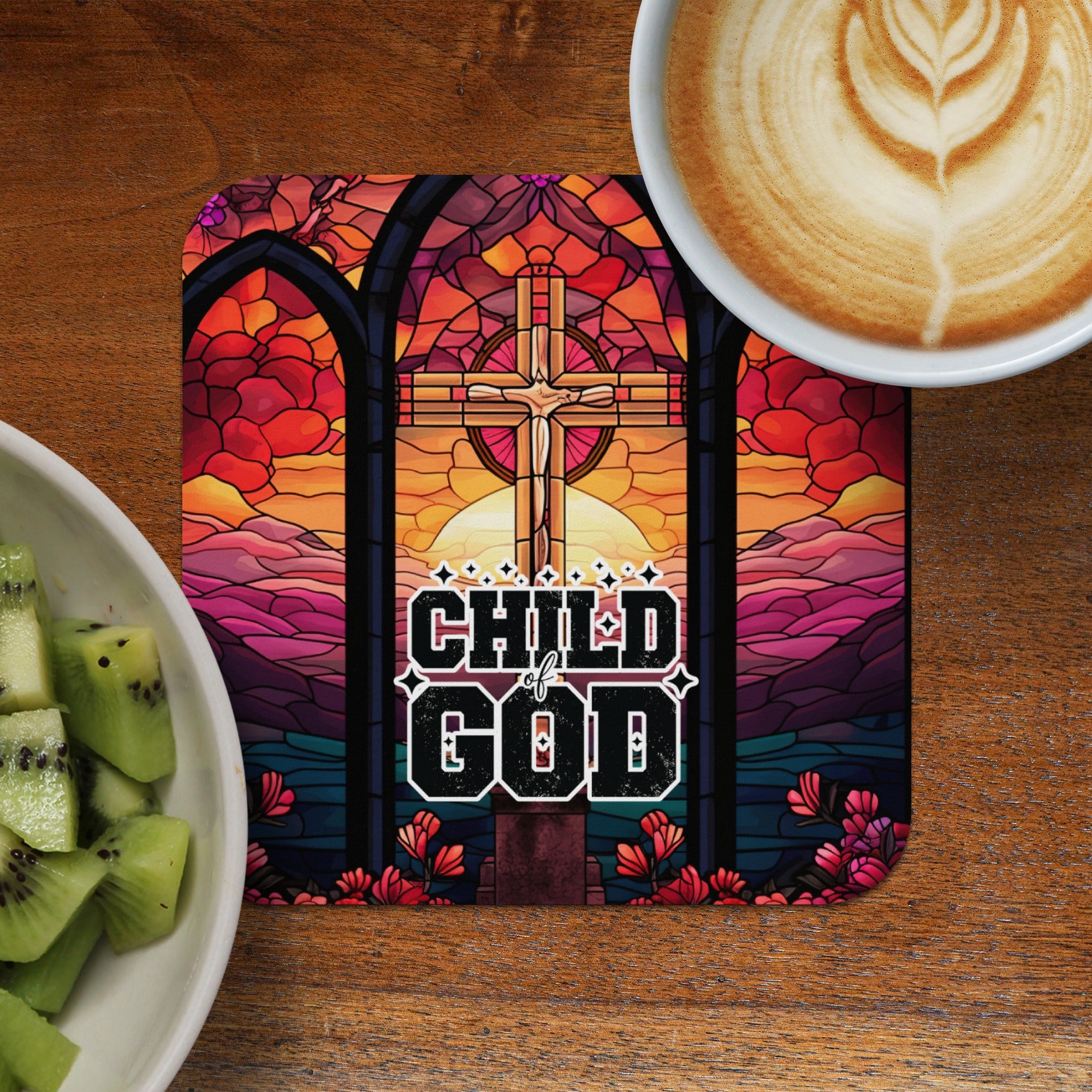 Stained glass cross with "Child of God" text, beside coffee and kiwi.