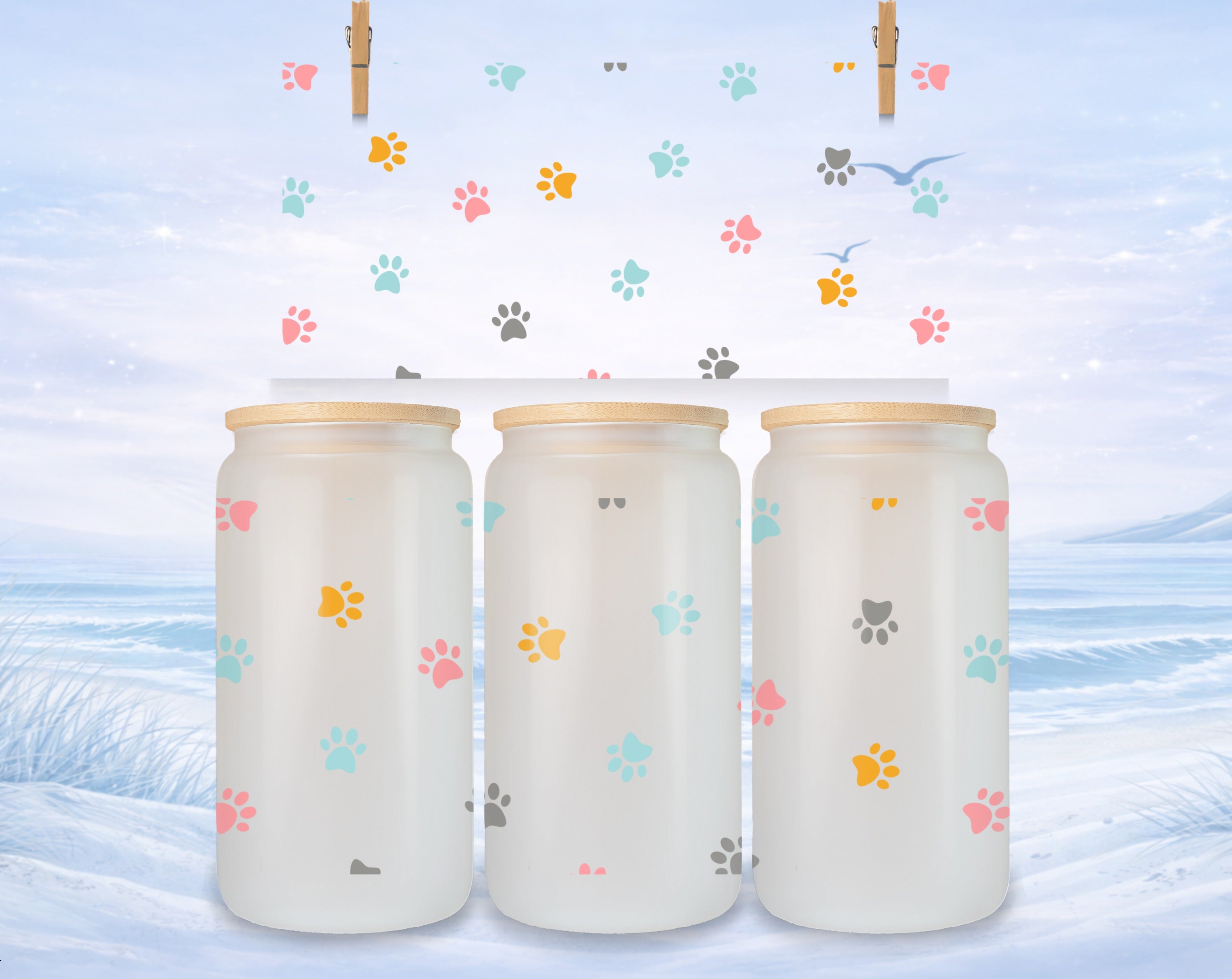 Three frosted glass mugs with colorful paw prints on a winter landscape background.