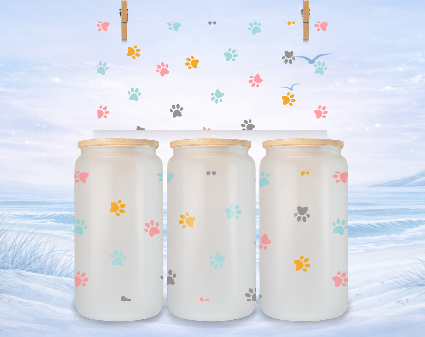 Three frosted glass mugs with colorful paw prints on a winter landscape background.