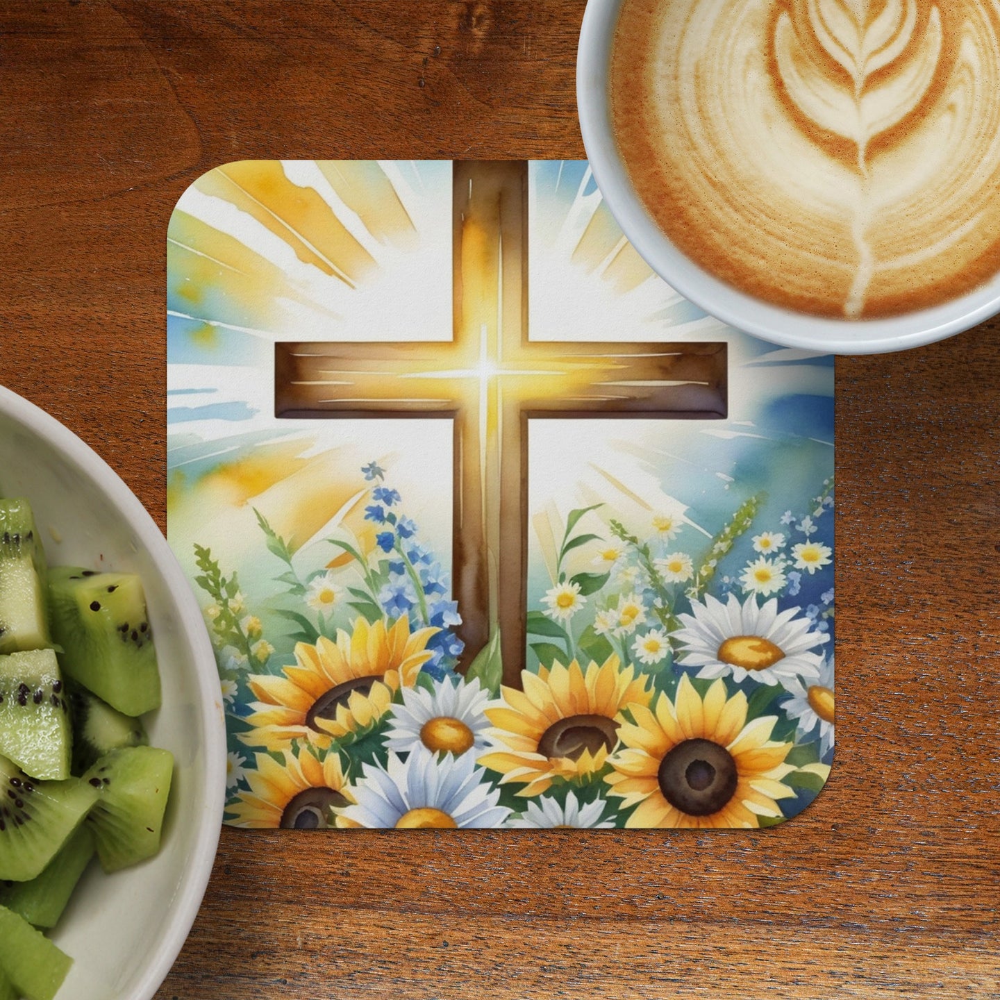 Watercolor cross with sunflowers, blue flowers, and sunburst over coffee and kiwi slices.