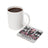 Mug of coffee next to a coaster with skull, roses, and wolves design.