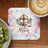 Coaster with wooden cross, lamb, and text "He is Risen" surrounded by flowers.