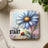 Blue daisy with ladybug and text "Just Start" on a coaster.