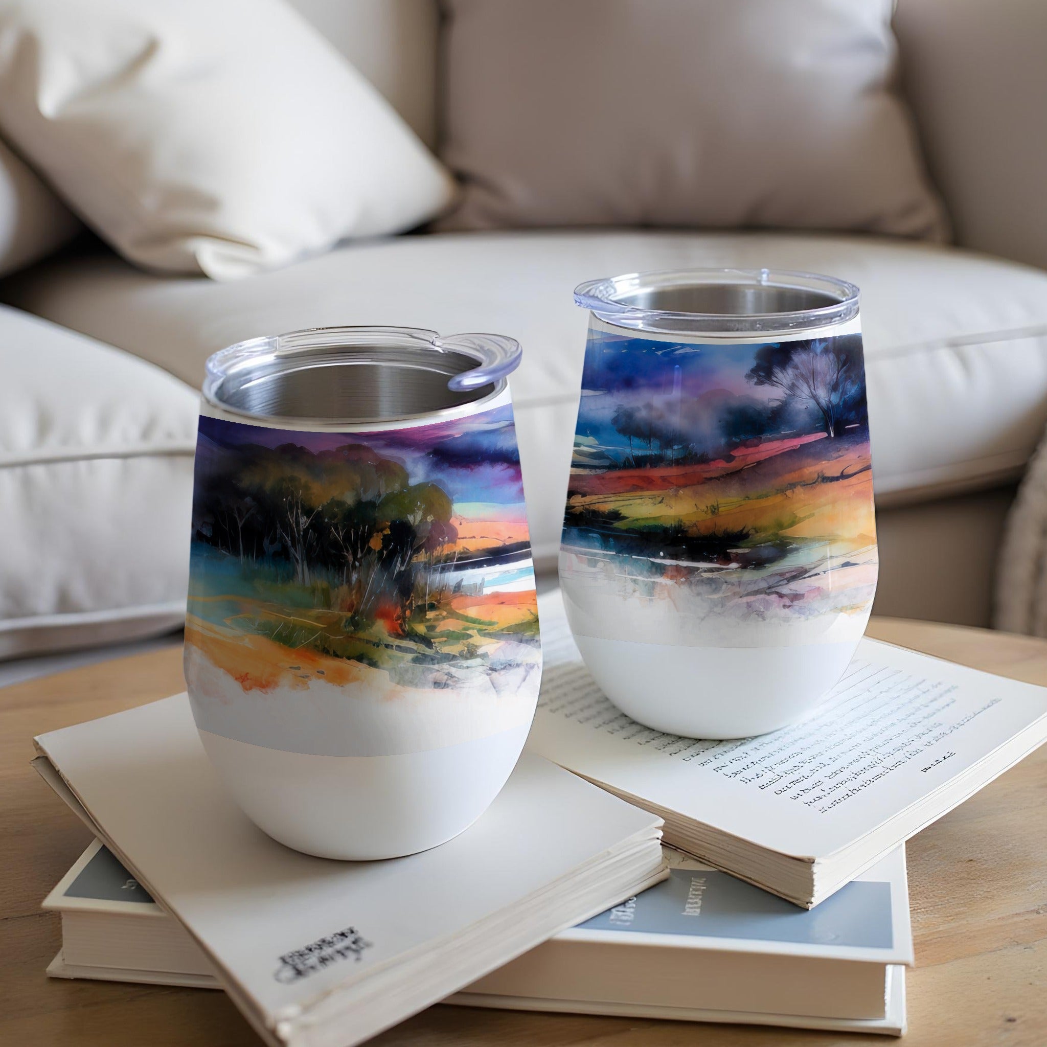Two tumblers with colorful abstract landscape art on a coffee table.