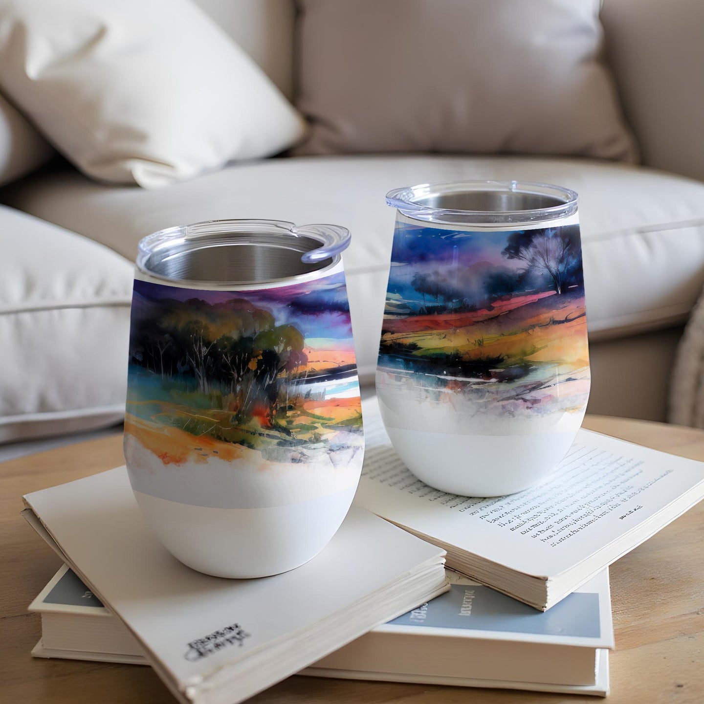 Two tumblers with colorful abstract landscape art on a coffee table.