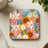 Square coaster with a retro floral pattern featuring smiley faces.