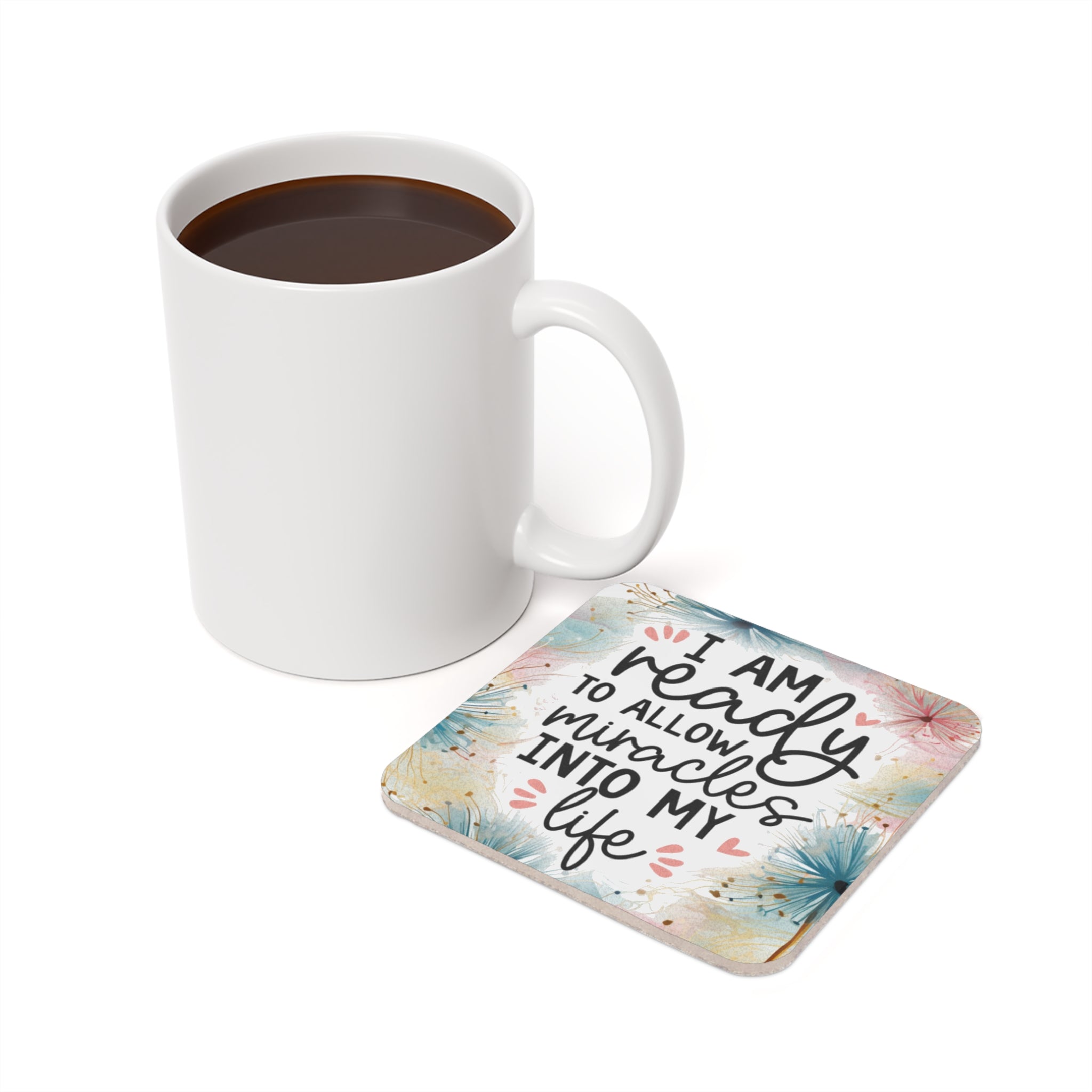 White mug of coffee next to a coaster with "I am ready to allow miracles into my life" text.