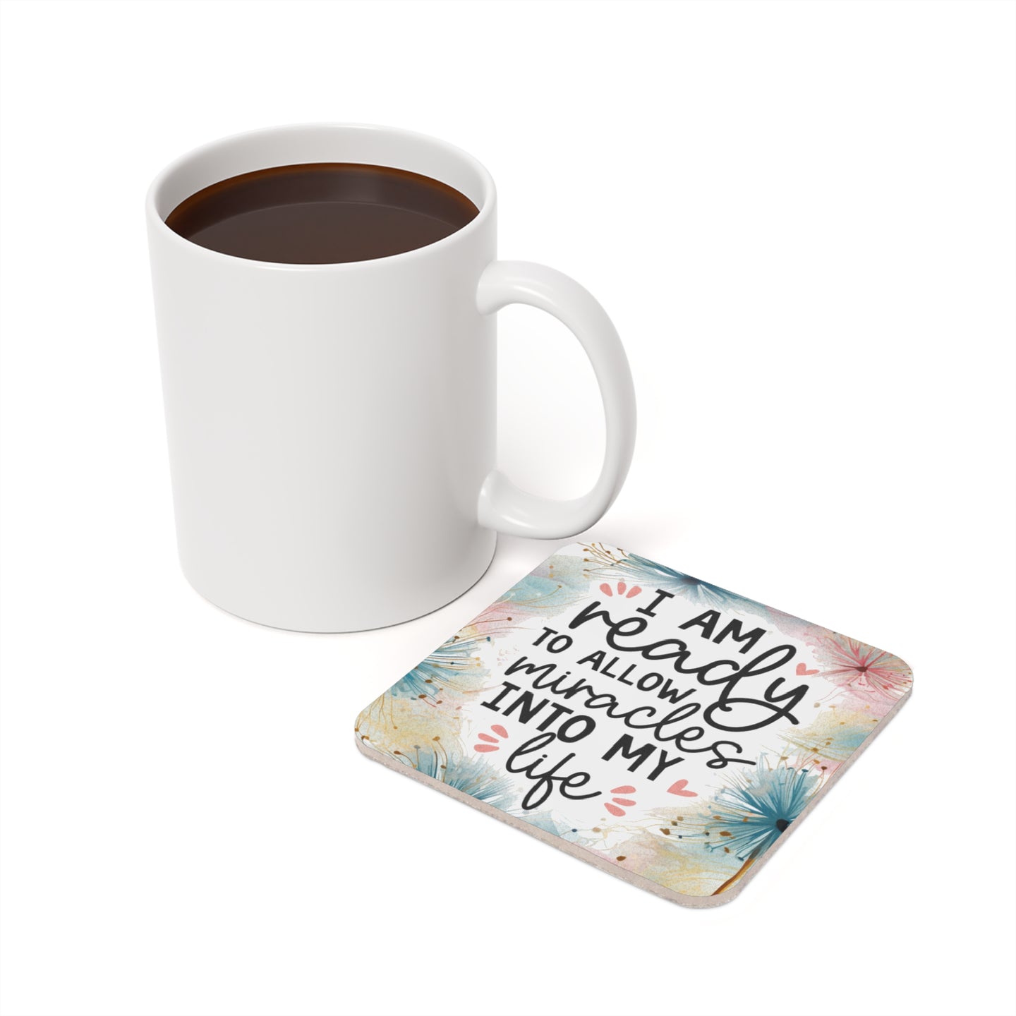 White mug of coffee next to a coaster with "I am ready to allow miracles into my life" text.