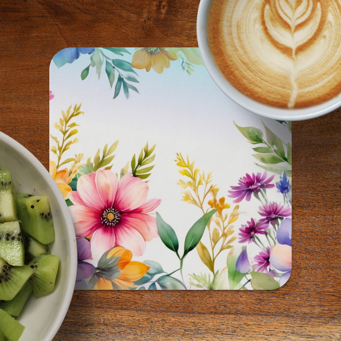 Floral watercolor placemat with coffee and kiwi fruit on a wooden table.
