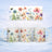 Mug with floral watercolor art, featuring poppies and wildflowers against a muted background.
