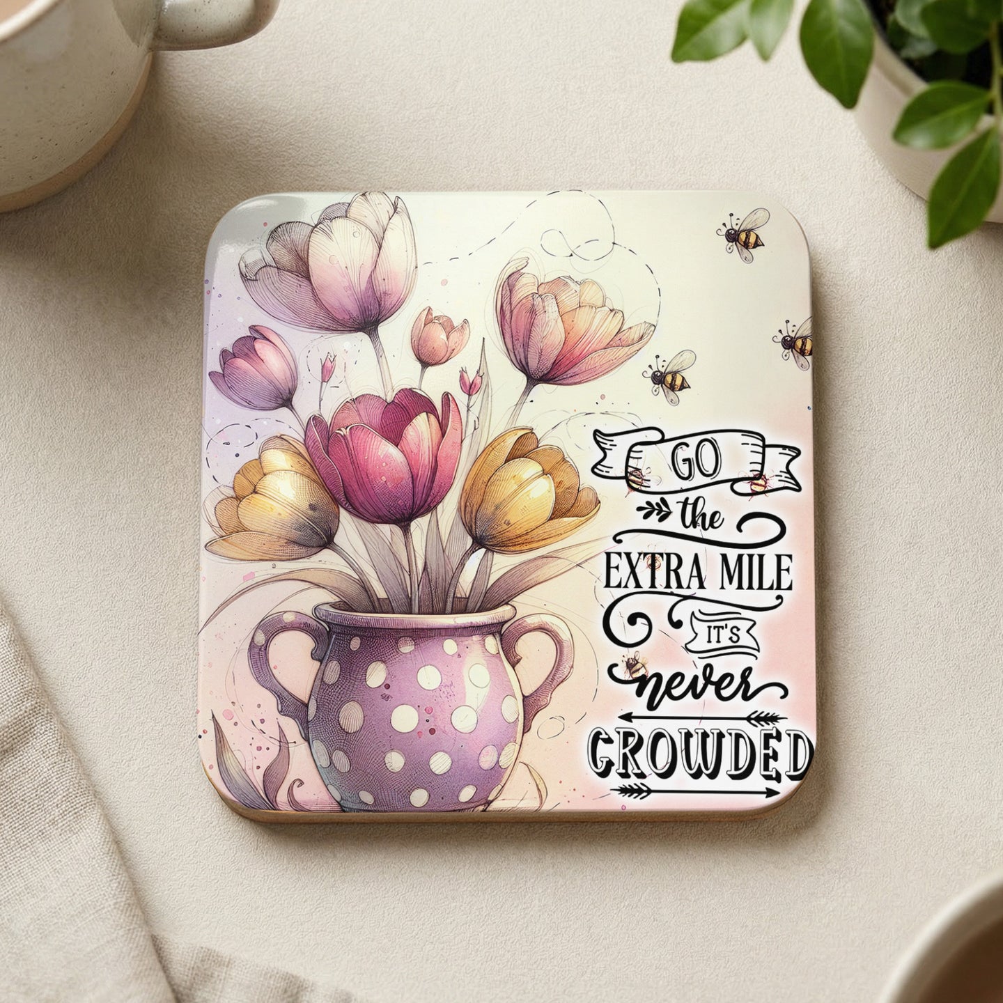 Coaster with pink and yellow tulips in polka dot vase and text "go the extra mile it's never crowded".