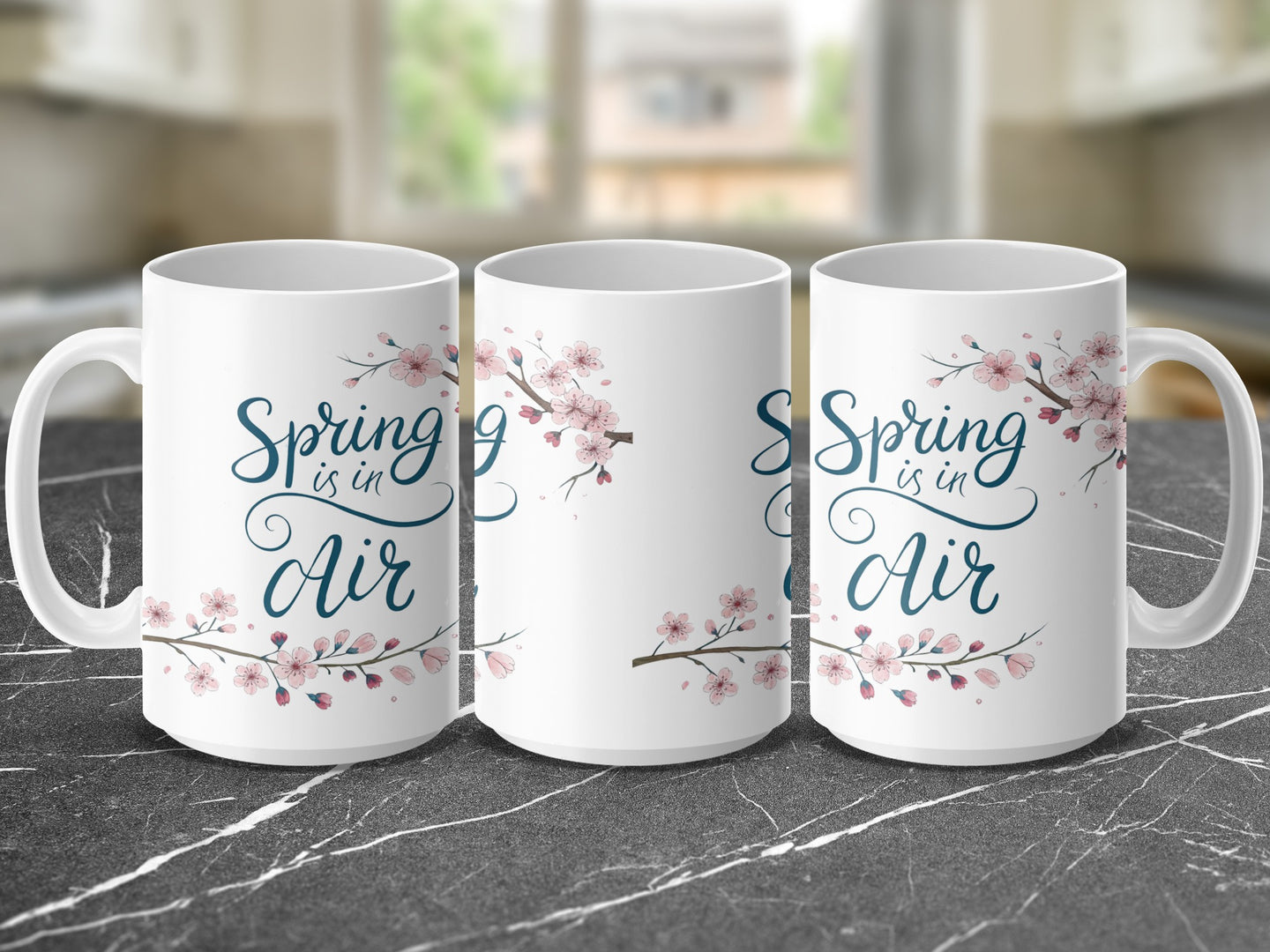White mug with "Spring is in Air" and pink cherry blossoms.