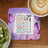 Coaster with "She Moms" text, Bible verses, and butterflies, next to kiwi slices.