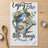 Bluebird on watering can wearing a straw hat, "Enjoy the little things" text.