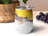 White tumbler with swirling yellow, gray, and black abstract art pattern.