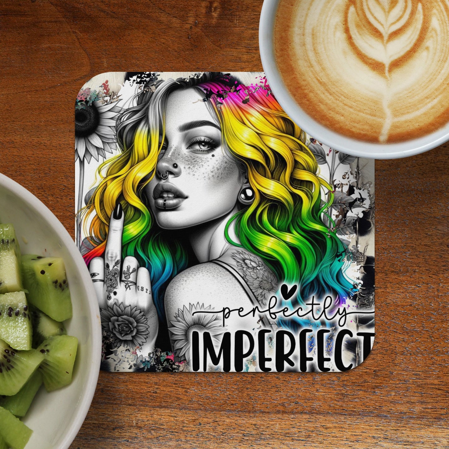 Coaster with woman with rainbow hair, text "perfectly IMPERFECT", and kiwi slices beside coffee.