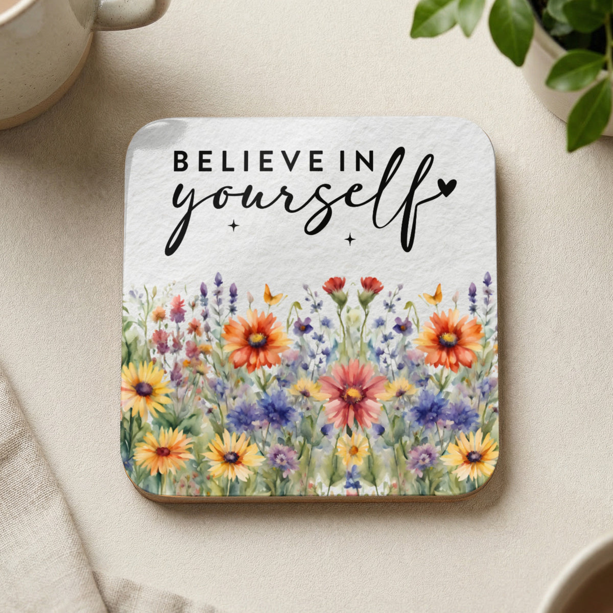 Coaster with watercolor wildflowers and "Believe in yourself" text.