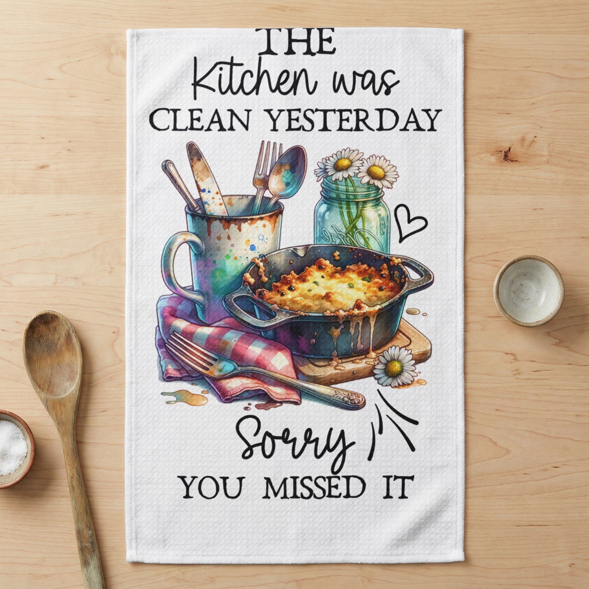 Kitchen towel with casserole and utensils, text "The kitchen was clean yesterday. Sorry you missed it."