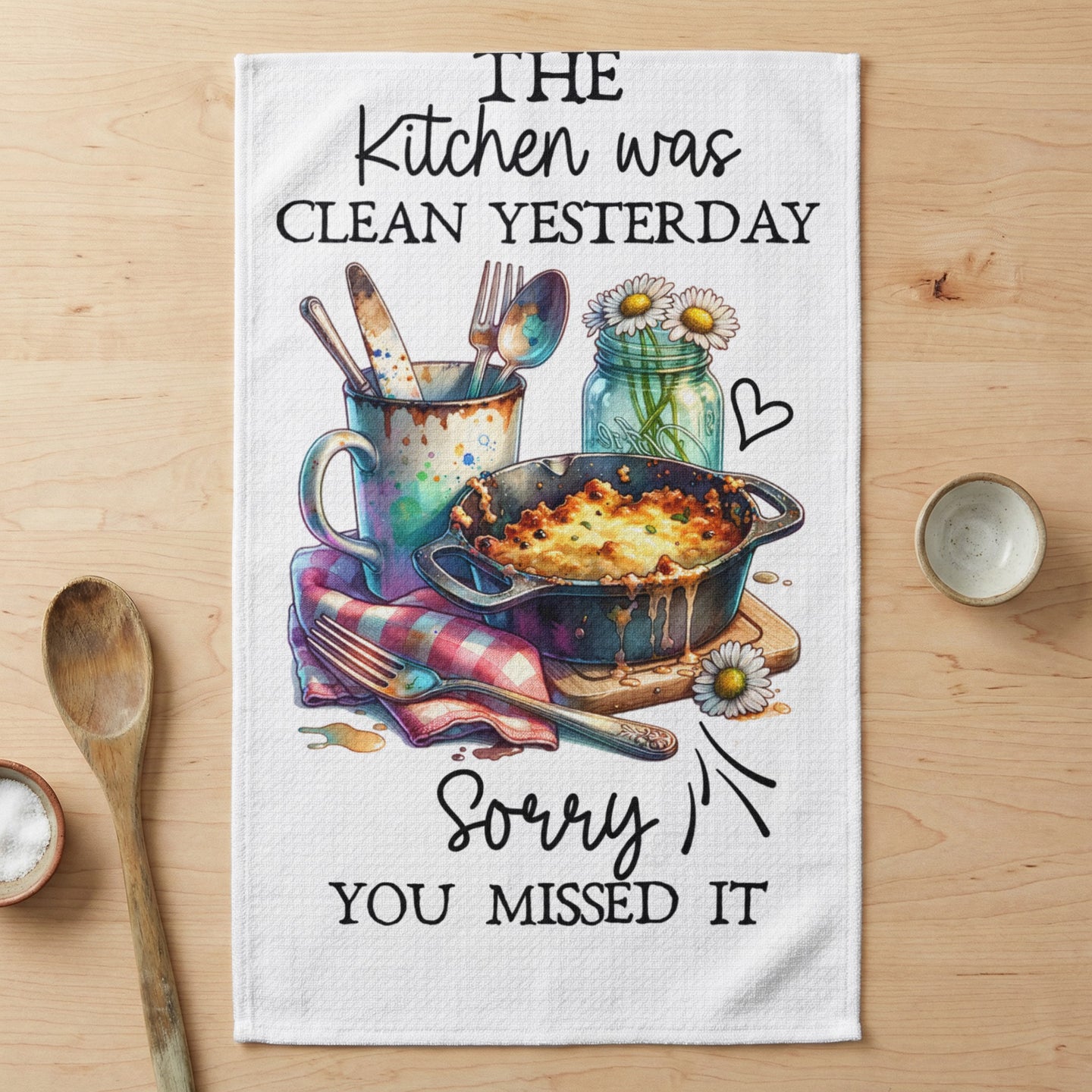 Kitchen towel with casserole and utensils, text "The kitchen was clean yesterday. Sorry you missed it."
