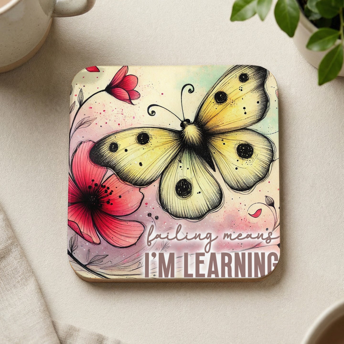 Square coaster with watercolor butterfly, pink flowers, and text "Failing means I'm learning."