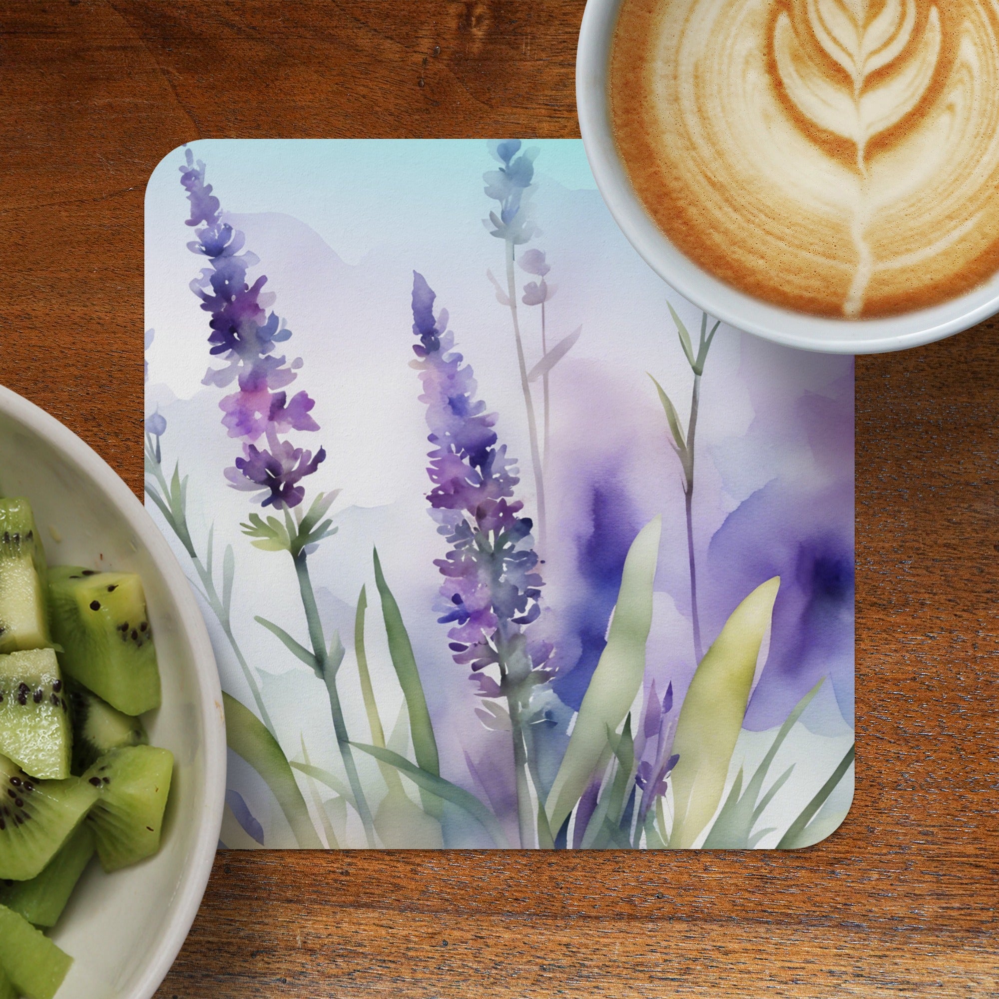 Watercolor lavender painting on a coaster next to kiwi and coffee.