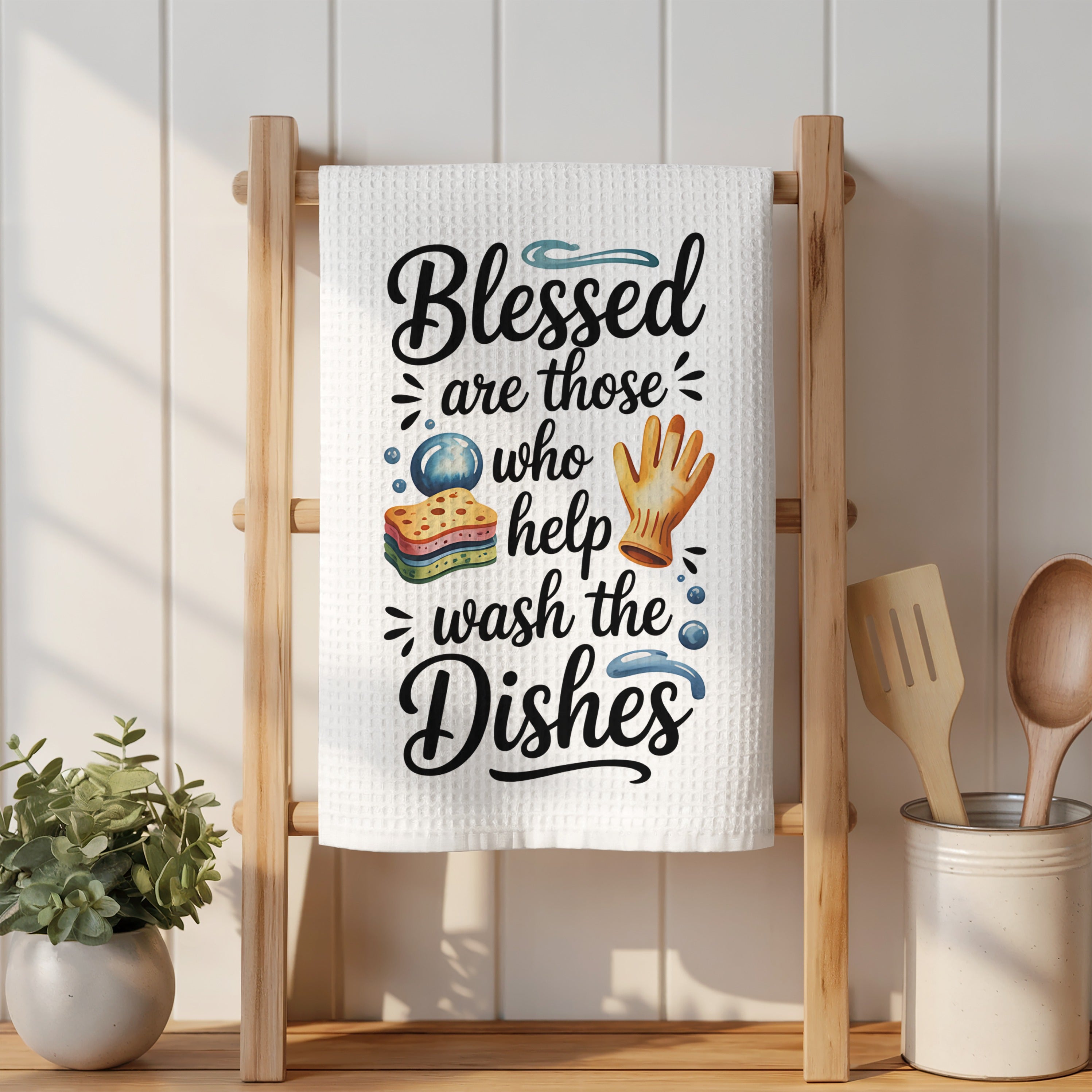 "Blessed are those who help wash the dishes" kitchen towel on a wooden rack.
