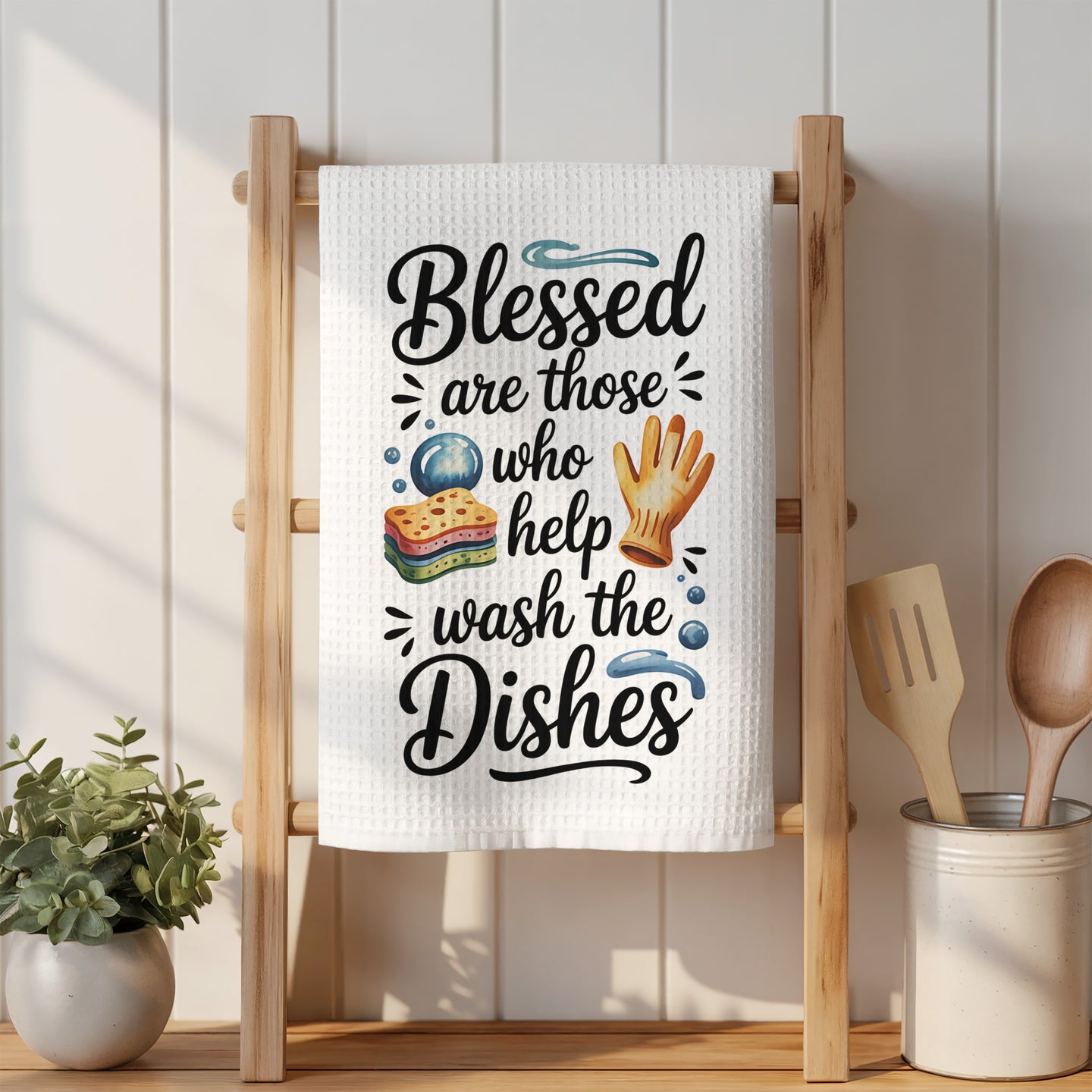 "Blessed are those who help wash the dishes" kitchen towel on a wooden rack.