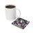 White mug beside a coaster with a witchy woman and skulls illustration.